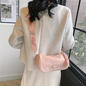 Pink retro cylinder crossbody bag with wide strap worn by model in a stylish setting