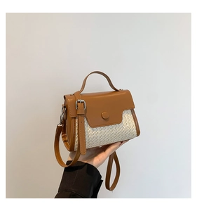 Detailed view of the textured straw and brown leather patchwork handbag with metallic buckle