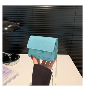 Détail du petit sac bleu clair pailleté avec bandoulière chaîne et finition brillante