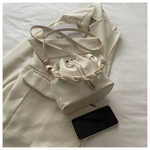 Détail d'un sac seau blanc effet marbre avec poignée tressée et boucles dorées chic