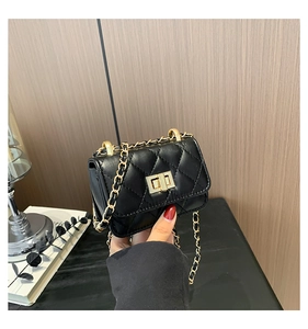 Close-up of black quilted chain bag with gold metal clasp held by a model
