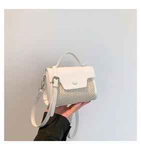 Detail of the chic two-tone straw patchwork small square handbag with top handle and strap