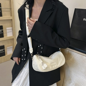 White crescent crossbody bag with wide shoulder strap shown on a fashion model