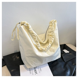 Detail of cream drawstring shoulder bag with pleated handle and metal zipper closure