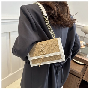 Detail of woven straw shoulder bag with white leather trim and gold tassel charm