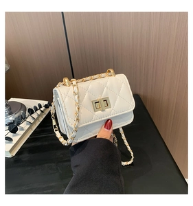 Detail of white quilted crossbody bag with golden chain strap and turn-lock closure