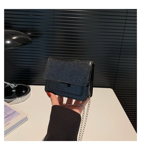 Détail du sac à paillettes noires avec bandoulière chaîne argentée et rabat magnétique