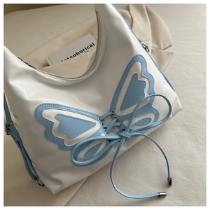 Detail of white and blue hobo bag with butterfly patchwork and decorative ribbon bow