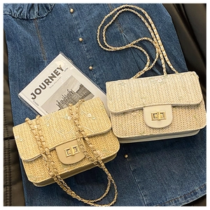 Detail of woven straw shoulder bag with floral embroidery and gold chain strap