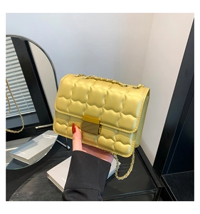 Detailed shot of yellow quilted shoulder bag featuring gold chain and metal buckle