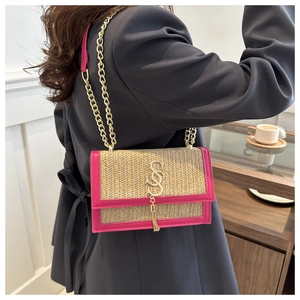 Detail of woven straw bag with pink leather trim and gold chain strap on a model