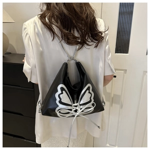 Close-up of silver butterfly embroidery and lace-up detail on a black leather backpack