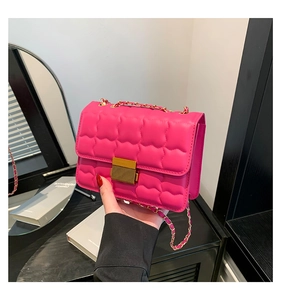 Detail of rose pink quilted crossbody bag with gold metal push-lock and chain strap