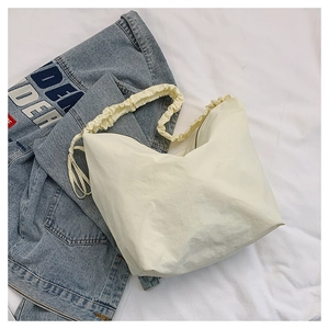 Macro shot of cream-colored nylon hobo bag with cloud-like pleated strap and drawstring