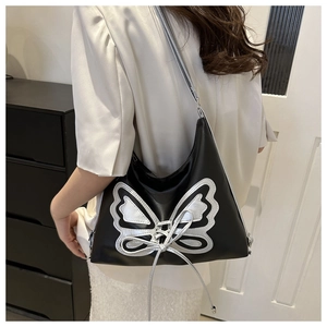 Detail of silver butterfly patch and ribbon bow on black leather underarm bag