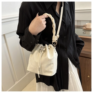 Détail du sac seau crème avec poignée tressée et cuir à texture marbrée élégante