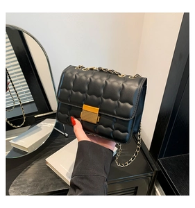 Detail of black quilted chain bag featuring elegant gold clasp and textured PU leather
