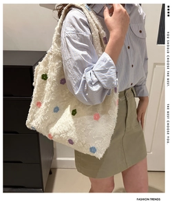 Détail d'un sac cabas blanc à franges avec broderies florales sur un mannequin