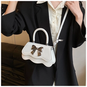 Détail du mini sac blanc avec bordure ondulée et boucle en forme de nœud métal