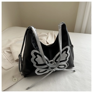 Detailed close-up of a black Y2K shoulder bag featuring a large silver butterfly patch