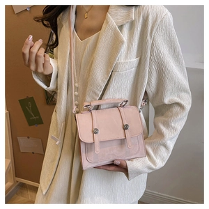 Detail of light pink structured crossbody bag with silver hardware on a model