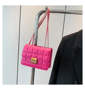 Close-up of pink quilted crossbody bag with golden buckle and metal chain strap