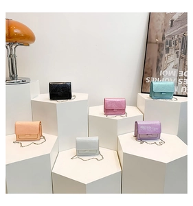 Groupe de six mini sacs à chaîne pailletés colorés sur des socles minimalistes