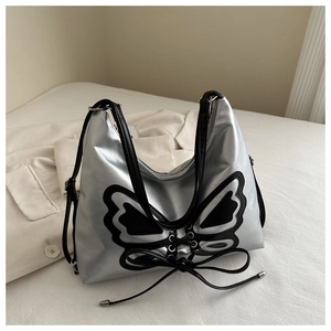 Close-up of silver crossbody bag featuring black butterfly applique and lace-up details