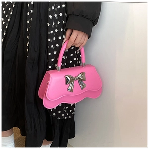 Détail du sac à main rose vif avec nœud argenté et base au design ondulé unique