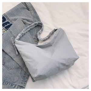 Detail of light blue nylon crescent bag featuring unique ruched strap design on denim