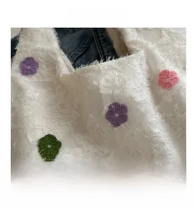 Détail macro du sac en tricot blanc avec broderies florales 3D et texture douce