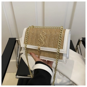 Detail of woven straw handbag featuring white leather trim and gold metal chain strap