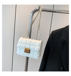 Detail of white quilted crossbody bag with golden metal buckle and chain strap