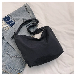 Detail of black nylon cloud bag with ruched strap on denim jacket backdrop