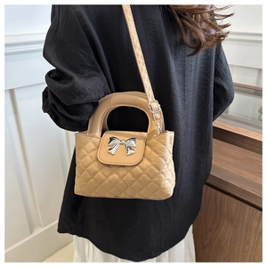 Detail of quilted leather handbag with bow metal buckle and adjustable shoulder strap