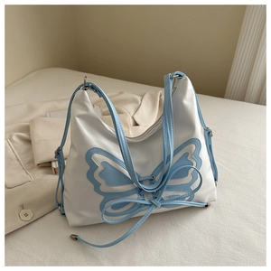 Detail of white PU leather hobo bag with blue butterfly patchwork and ribbon bow