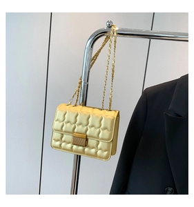 Close-up of a pale yellow quilted crossbody bag featuring a vintage gold metal clasp