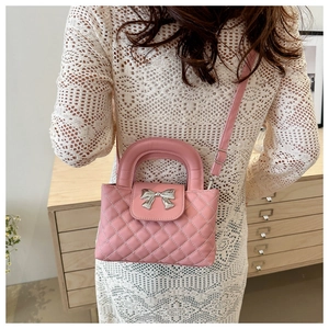 Detail of pink quilted handbag with silver bow hardware and adjustable shoulder strap