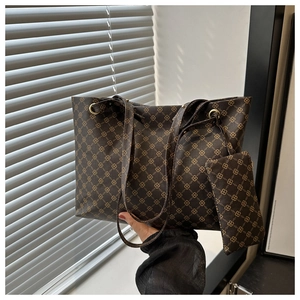 Detail of a large leather tote bag with gold geometric patterns and matching pouch