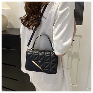 Borsa a tracolla trapuntata con finiture dorate indossata da una modella in ambiente interno
