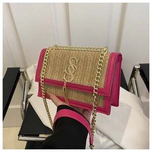 Detail of woven straw shoulder bag with pink leather trim and gold SOS logo tassel