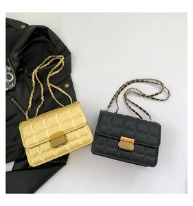 Detail view of wavy quilted chain bag featuring golden rectangle metal lock and PU texture