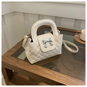 Detailed view of quilted tote bag featuring a silver bow clasp and interior storage space