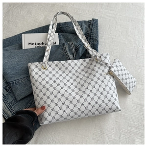 Detail of white tote bag set with black clover pattern on denim and book prop