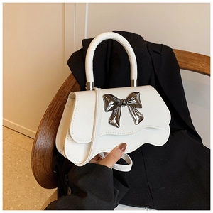 Détail du sac à main blanc avec rabat à bord ondulé et fermoir nœud métallique