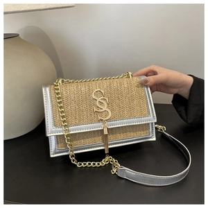 Detailed close-up of woven straw handbag with silver metallic trim and gold logo