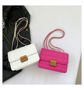 Close-up of quilted crossbody bags in white and rose pink with gold chain straps
