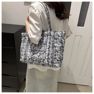 Close-up of black and white houndstooth tweed tote bag carried on a model's shoulder