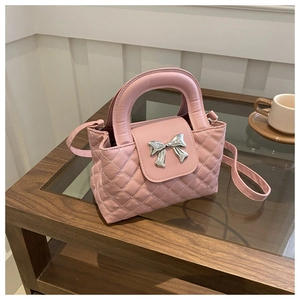 Detailed shot of pink quilted handbag with silver bow hardware on a wooden table