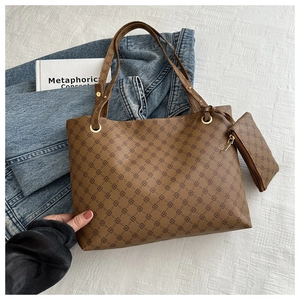 Detail view of brown monogram tote bag set with matching zipper pouch on denim background